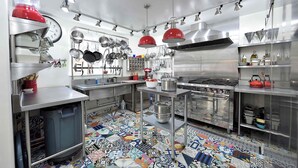 Una cocina moderna con electrodomésticos de acero inoxidable, una variedad de ollas y sartenes colgadas en la pared, y un piso de baldosas coloridas.