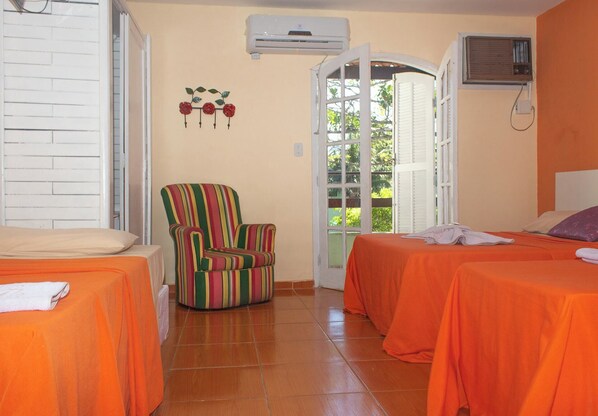 A room with two beds, a striped armchair, an air conditioning unit, and a door leading outside. - Pousada Recanto Shangri-lá (Cabo Frio)