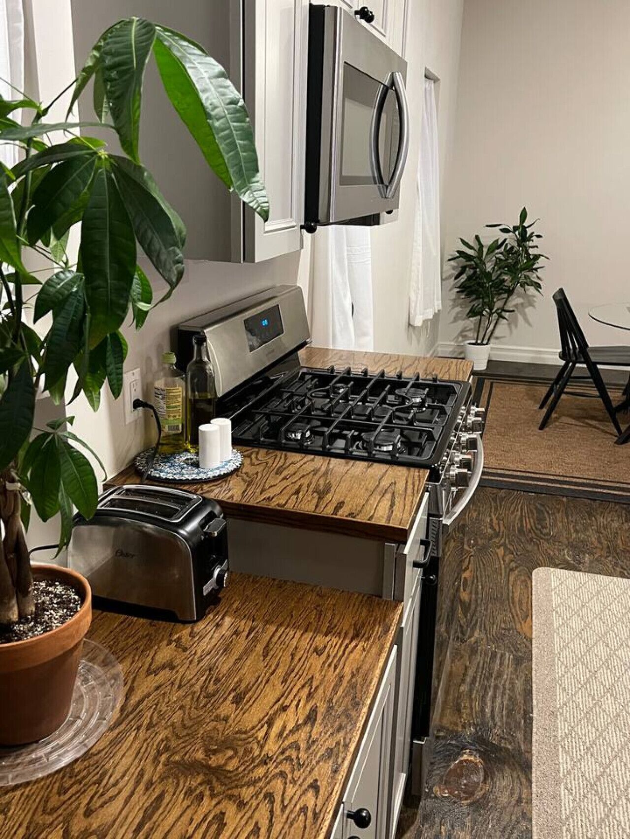 A kitchen with a wooden countertop, a stove, a toaster, and a microwave.