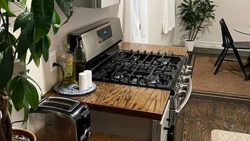 A kitchen with a wooden countertop, a stove, a toaster, and a microwave.