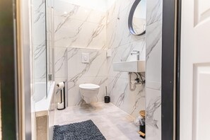 Un baño con paredes de mármol, un inodoro, un lavamanos y un espejo.