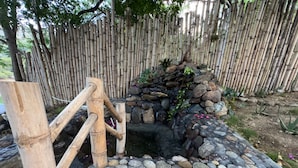 A traditional stone water feature with a bamboo fence in the background. - Glamping Lake San Juan (San Juan de la Maguana)