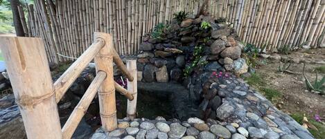 A traditional stone water feature with a bamboo fence in the background.