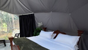 A single bed in a tent with a grey canopy, a wooden frame, and a green throw blanket. - Glamping Lake San Juan (San Juan de la Maguana)