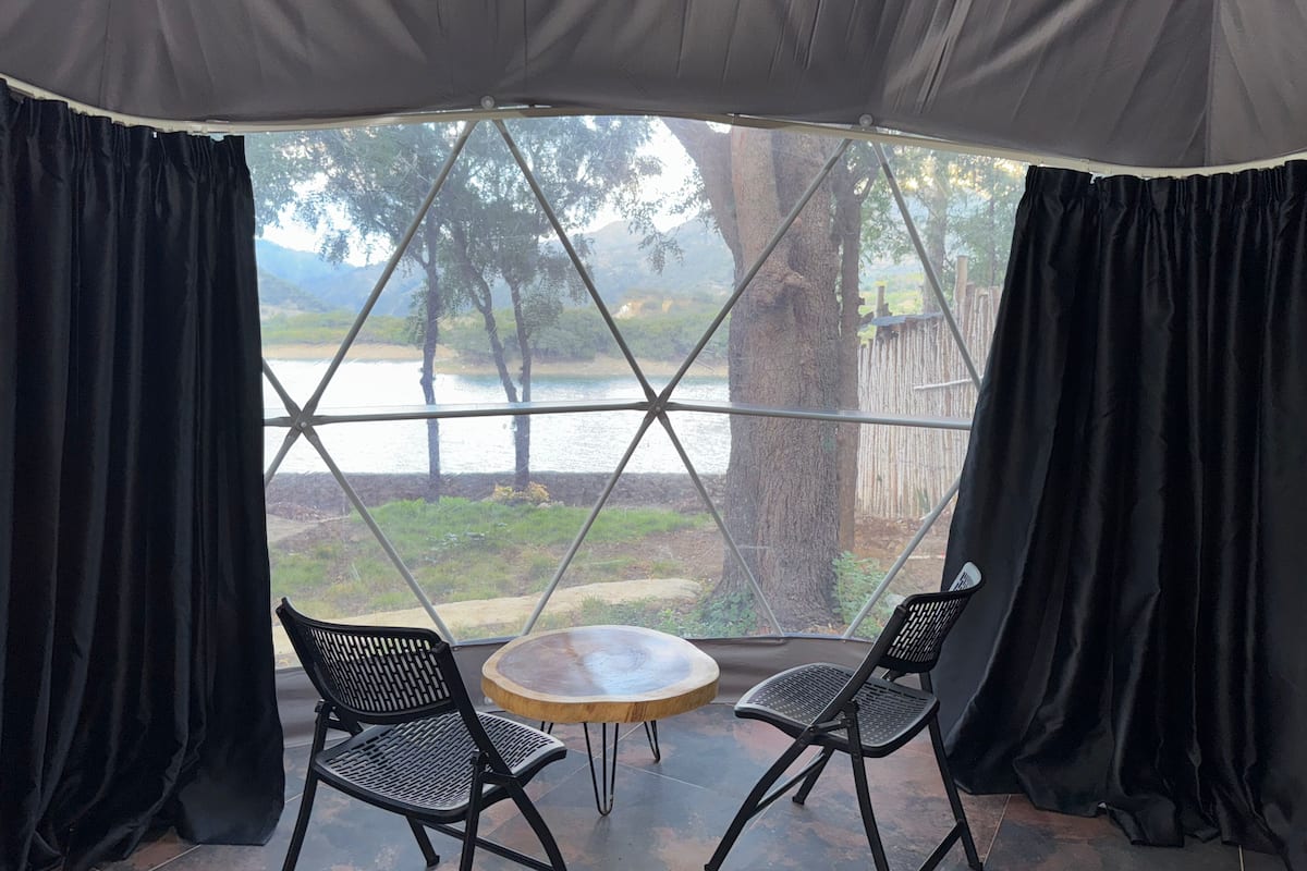 Ein Zimmer mit einem großen Fenster, zwei Stühlen und einem runden Tisch.