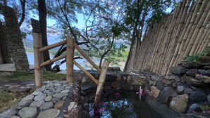 A traditional Japanese garden with a stone pond, bamboo structures, and a stone wall. - Glamping Lake San Juan (San Juan de la Maguana)