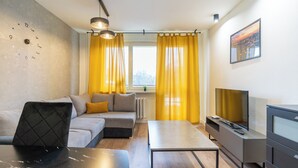 Ein modernes Wohnzimmer mit einer Couch, einem Couchtisch, einem Fernseher und einer Wanduhr.