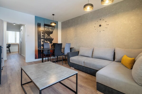 Un salon moderne comprenant un canapé, une table basse et un coin repas avec des chaises.
