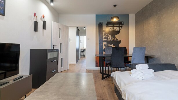 Ein modernes Hotelzimmer mit Bett, Schreibtisch, Stuhl, Fernseher und Kleiderschrank.