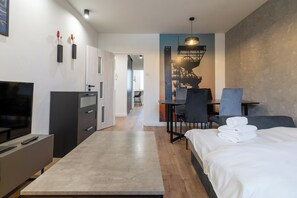 Une chambre d’hôtel moderne équipée d’un lit, d’un bureau, d’une chaise, d’une télévision et d’une armoire.