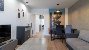 Ein modernes Wohnzimmer mit einer Couch, einem Fernseher und einem Essbereich mit Stühlen und einem Tisch.