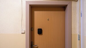 Eine hölzerne, geschlossene Tür mit einem Schlüsselschloss und einer kleinen elektronischen Tastatur.