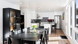 A modern kitchen with white cabinets, a black dining table, and a black cabinet with glass doors. - Payday at Park City, Luxury Renovated Townhome, Walk to Silver Star Lift, New Bullfrog Spa (Park City)