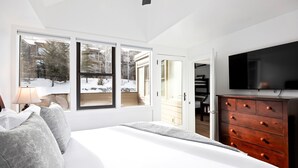 A bedroom with a large bed, a dresser, a TV, and a window with a view of a snowy landscape. - Payday at Park City, Luxury Renovated Townhome, Walk to Silver Star Lift, New Bullfrog Spa (Park City)