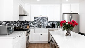 A modern kitchen with white cabinets, a tiled backsplash, and a stainless steel refrigerator. - Payday at Park City, Luxury Renovated Townhome, Walk to Silver Star Lift, New Bullfrog Spa (Park City)