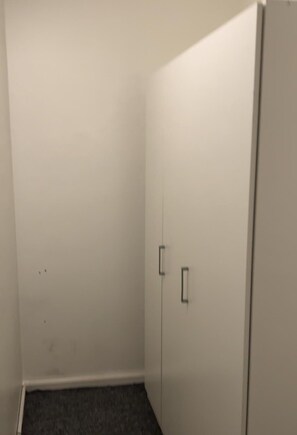 Simple, functional space with a single door and dark carpeted floor.