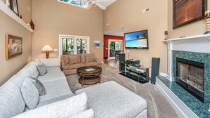 A living room with a sectional sofa, a coffee table, a fireplace, and a television.