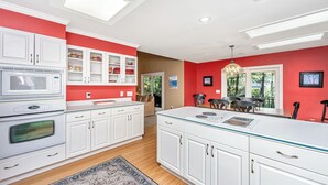 Una cocina moderna con armarios blancos, una isla grande y una pared de acento roja.