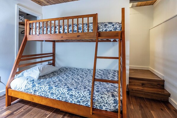 Una cama individual con estructura de madera y ropa de cama estampada con motivos florales.