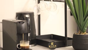 Une machine à café, une tasse, une plante en pot et une enseigne portant l’inscription « Elite Hotel ».