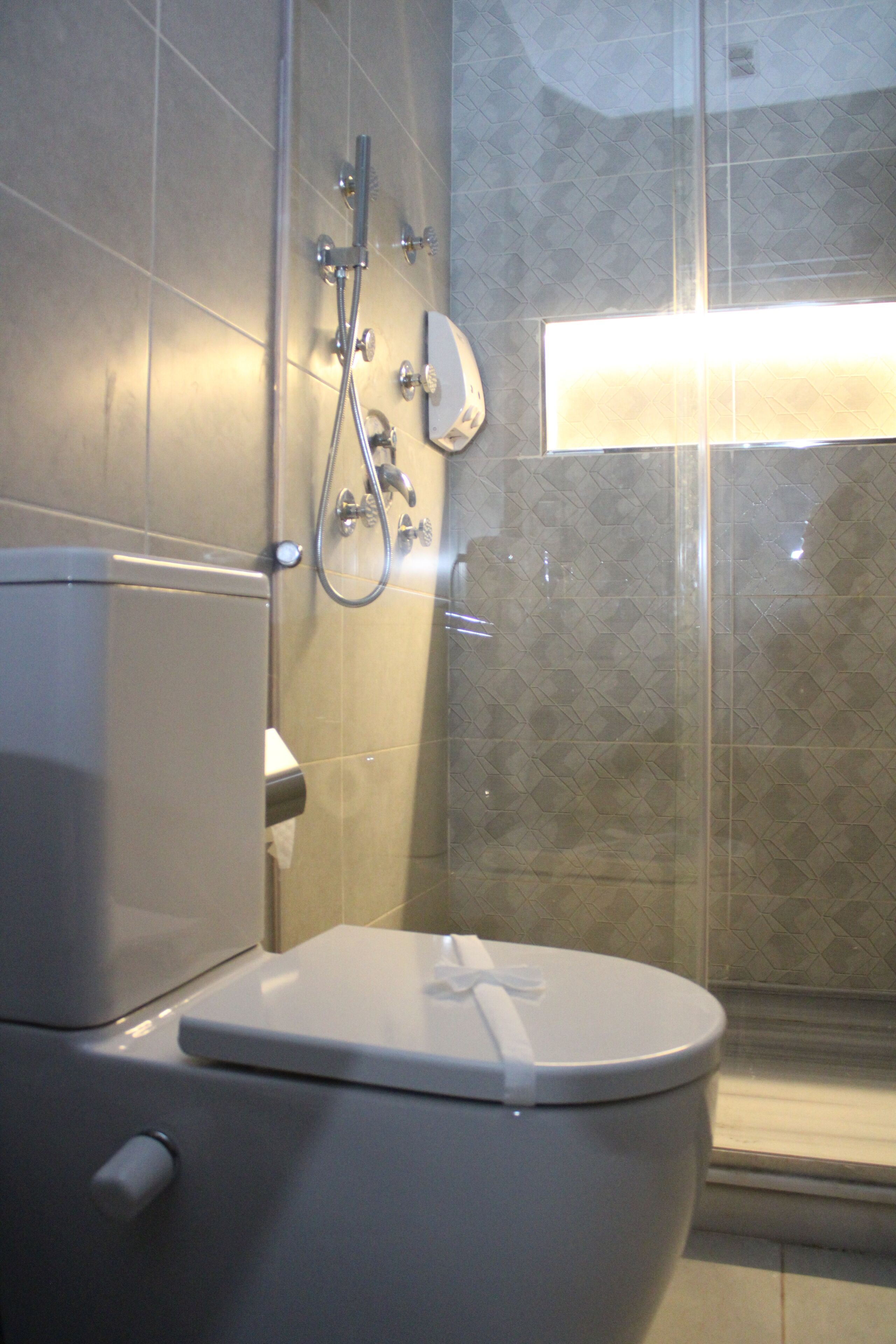 A modern bathroom with a toilet, shower, and a glass-enclosed shower area.