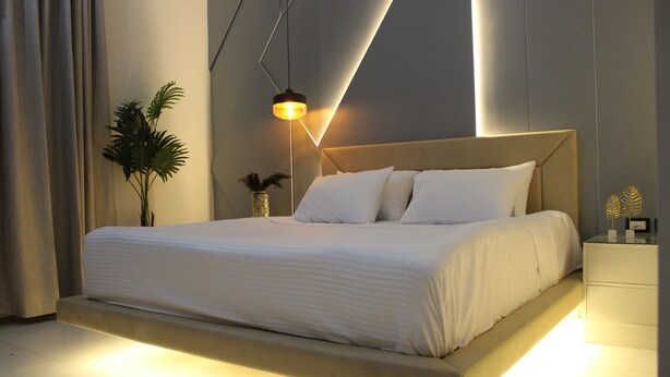 Une chambre moderne avec un grand lit, une table de chevet et un luminaire suspendu.