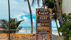 Un panneau indiquant « Playa La Parede » et « Restaurant de surf », signalant un établissement situé en bord de mer avec vue sur l’océan.