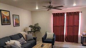A living room with a sofa, armchair, coffee table, and a ceiling fan.