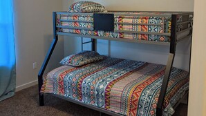 A bunk bed with a ceiling fan and patterned bedding.