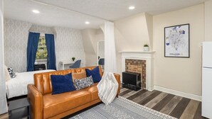 A modern living room with a leather sofa, a fireplace, and a map of Columbus on the wall. - Cozy Studio Near Children’s Hospital, Kitchen & Laundry (Columbus)