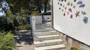 Una escalera conduce a un espacio cubierto con un muro decorado con motivos marinos.
