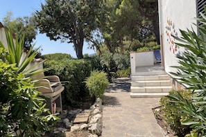 Un camino de piedra que lleva a un edificio con escalones y una pequeña zona de estar al aire libre.