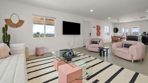 A modern living room with a sofa, two armchairs, a coffee table, and a TV mounted on the wall. - Joshua Tree Oasis • Cowboy Pool • Hot Tub • 5 Private Acres (Yucca Valley)