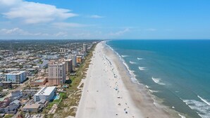 A coastal cityscape with a long beach, high-rise buildings, and a clear blue sky.