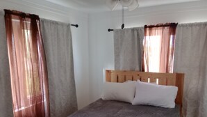 Ein Einzelbett mit Holz-Kopfteil und weißen Kissen in einem Zimmer mit beige gefärbten Wänden und einem gemusterten Boden.