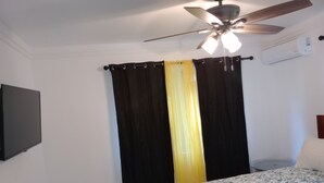 Ein Schlafzimmer mit einem Bett, einem Deckenventilator und einer Klimaanlage.
