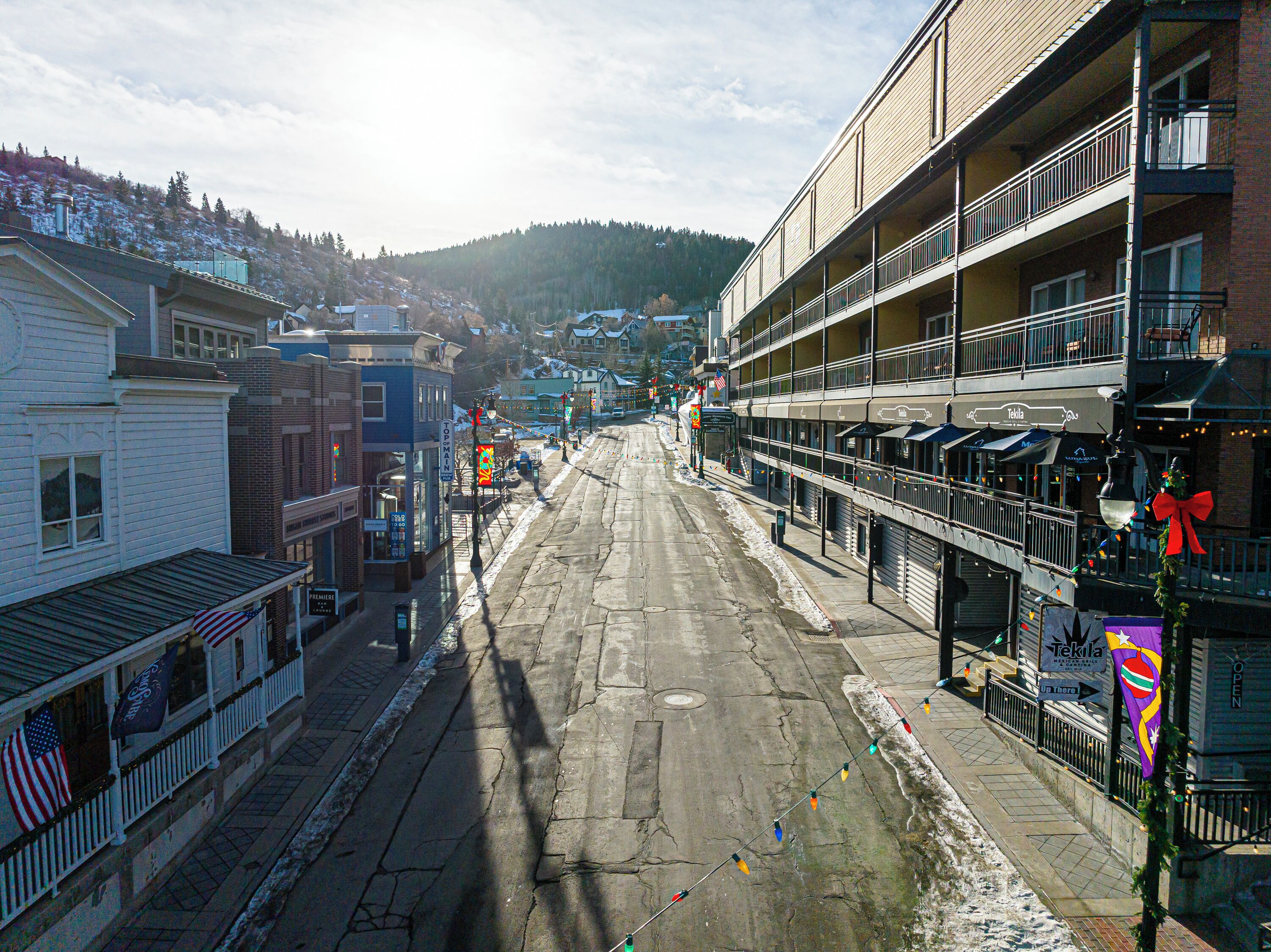 Eine Straße mit Gebäuden, darunter ein zweistöckiges Haus mit Balkonen und ein Eckhaus mit einer Veranda.