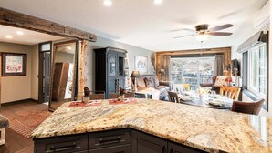 A kitchen with a granite countertop, wooden ceiling beams, and a dining area with a table set for four. - Rustic Luxe on Main | Spa, Dining & Charm On-Site at the Treasure Mountain Inn (Park City)