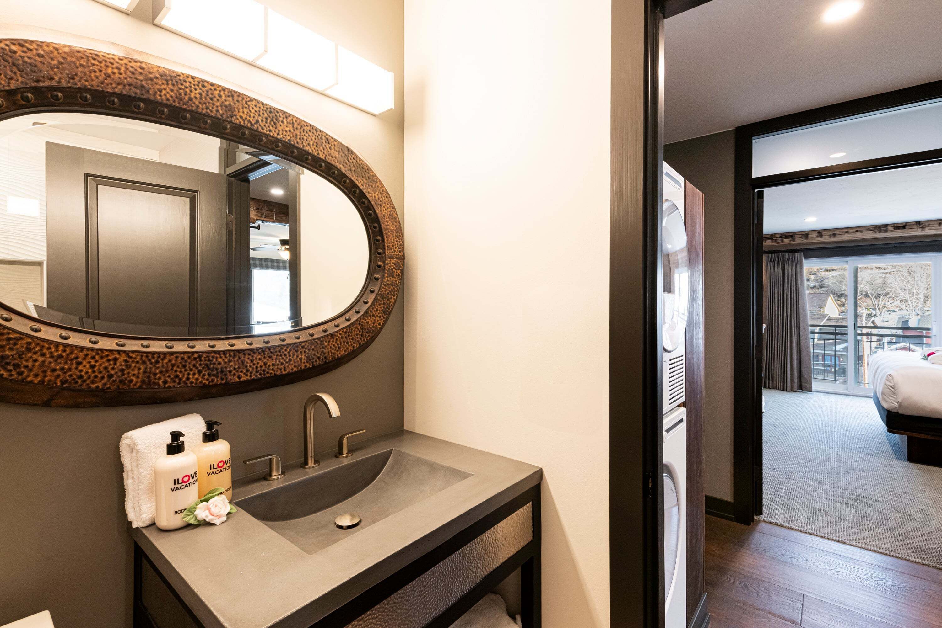 A bathroom with a large oval mirror, a sink, and two bottles of lotion.
