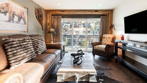 A living room with a sofa, armchair, coffee table, and a TV. - Rustic Luxe on Main | Spa, Dining & Charm On-Site at the Treasure Mountain Inn (Park City)