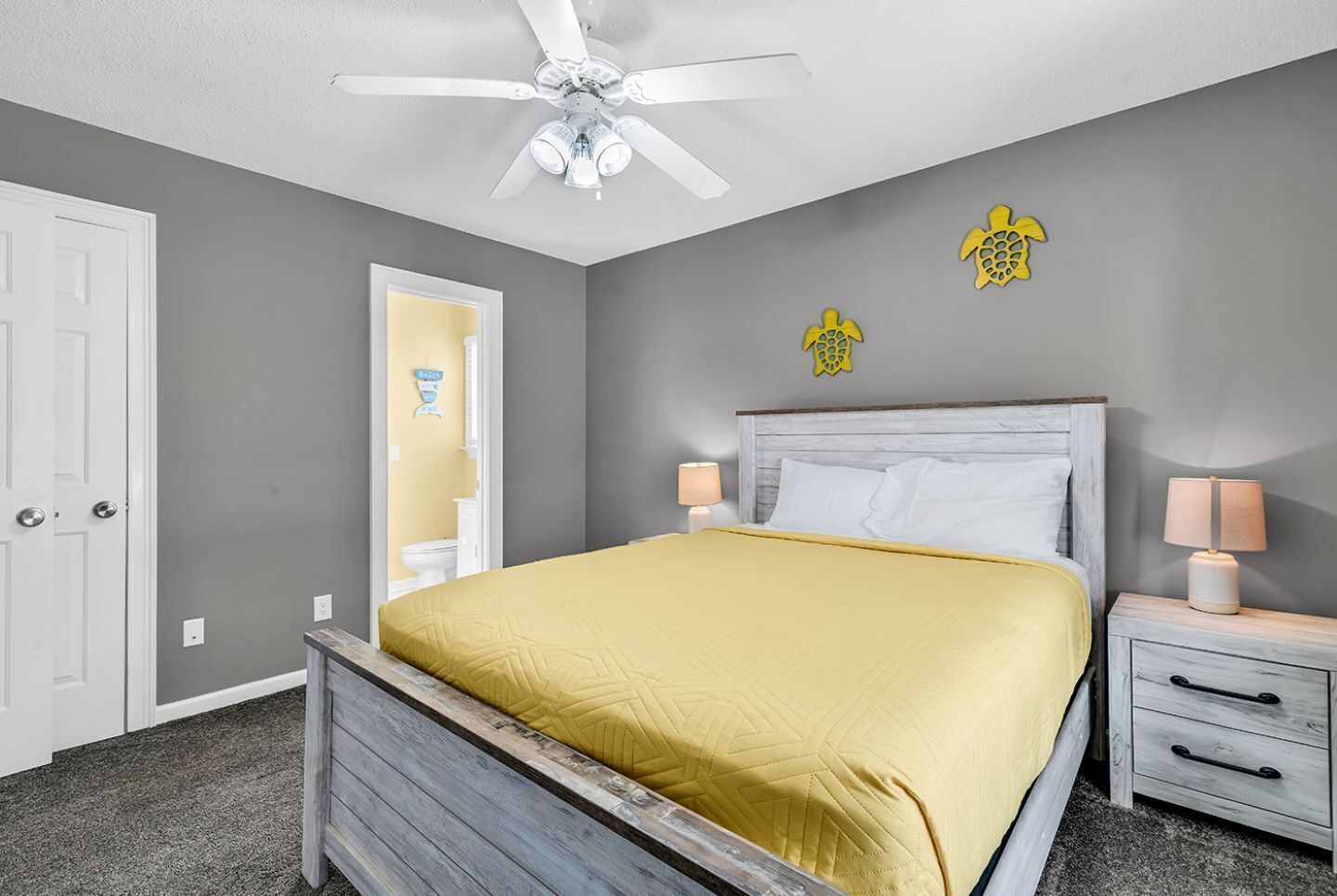 A bedroom with a bed, a nightstand, a ceiling fan, and a door.