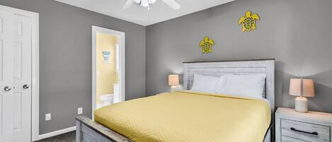 A bedroom with a bed, a nightstand, a ceiling fan, and a door.