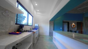 Een moderne keuken met een groot raam, een koffiezetapparaat en een blauw aanrecht.