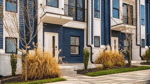 A row of townhouses with a brick facade, large windows, and a small front yard with plants. - Monty by Avantstay 4bdr 4ba, Balcony w/ Outdoor Seating, 5mins to DT (Nashville)