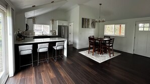 A spacious kitchen with a large island, dark wood flooring, and a dining area with a chandelier. - Redlands farm (Oregon City)