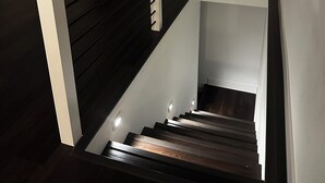 A modern staircase with dark wooden steps and white railings, leading to a landing area with a door. - Redlands farm (Oregon City)
