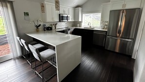 A modern kitchen with a central island, stainless steel appliances, and a large window providing natural light. - Redlands farm (Oregon City)