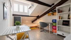 Een kleine kamer met een hoogslaper, een bureau en een boekenkast.
