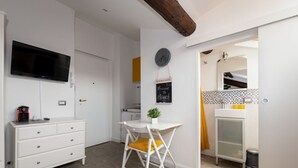 Een kleine keuken met een witte tafel, een klok en een bord waarop staat 'Welcome to Milano'.
