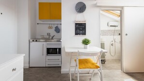 Een moderne keuken met witte kasten, een geel bovenkastje, een klok en een bord met een welkomstdroog voor Milaan.